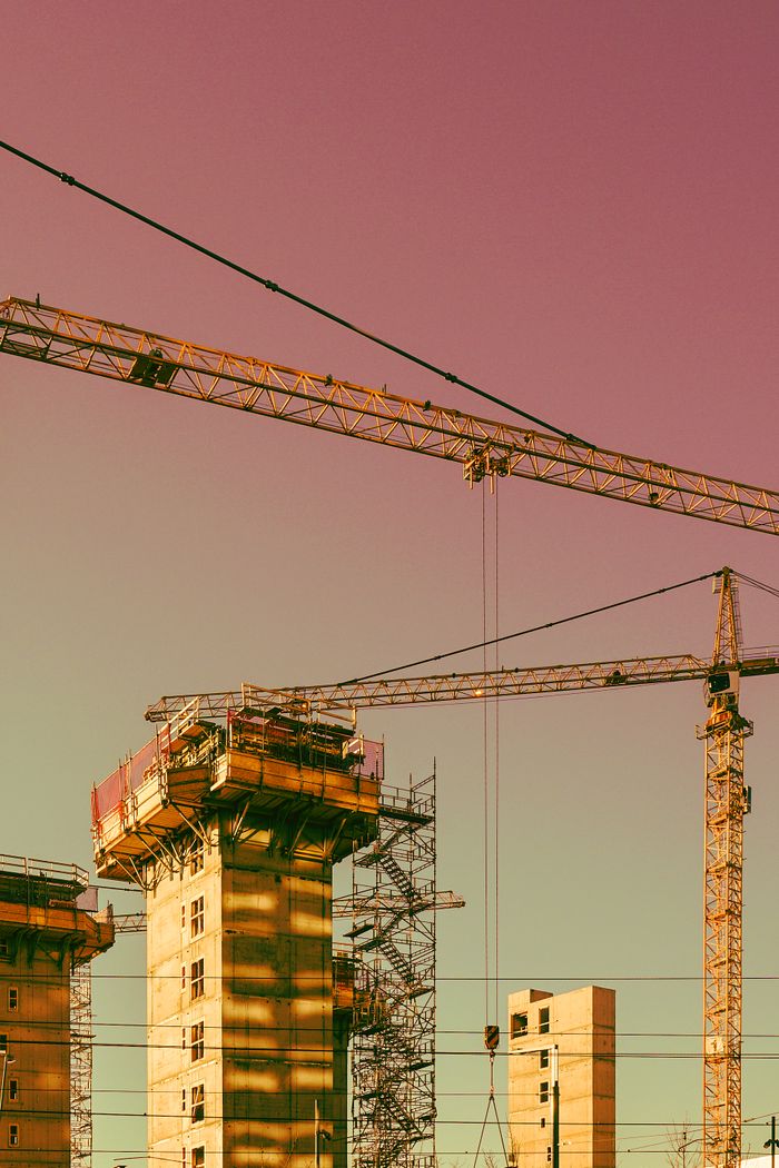 why-choose-us-03 Vertical urban construction scene in Oslo featuring cranes and scaffolding.