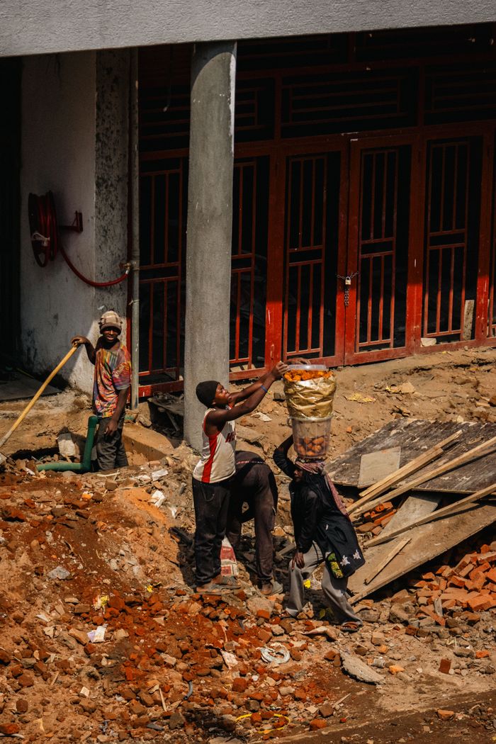 A group of construction workers engaged in manual labor on a city building site.